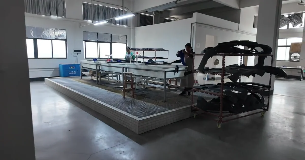 Carbon fiber automotive body panel positioned in a factory assembly area.