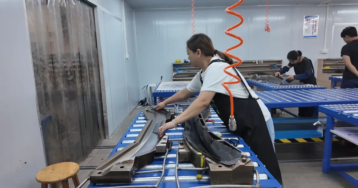 Technician checking a carbon fiber automotive part on a workshop fixture.