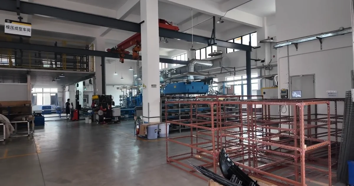 Carbon fiber automotive parts production floor with workstations and storage frames.