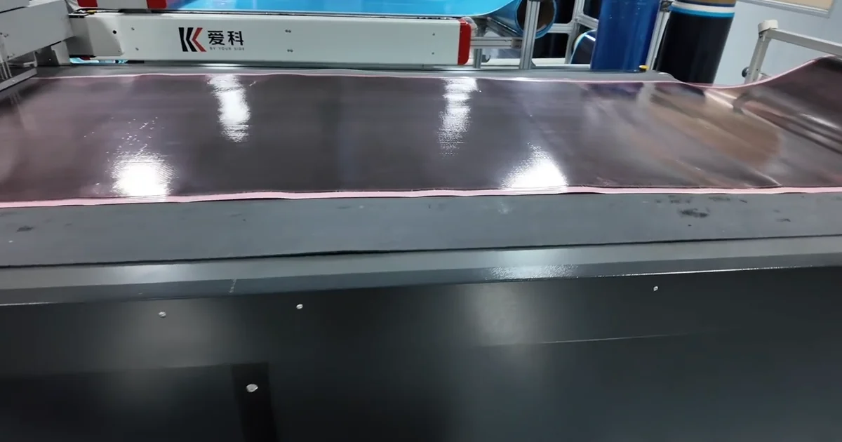 Gloss carbon fiber prepreg sheet positioned on a layup table before molding.